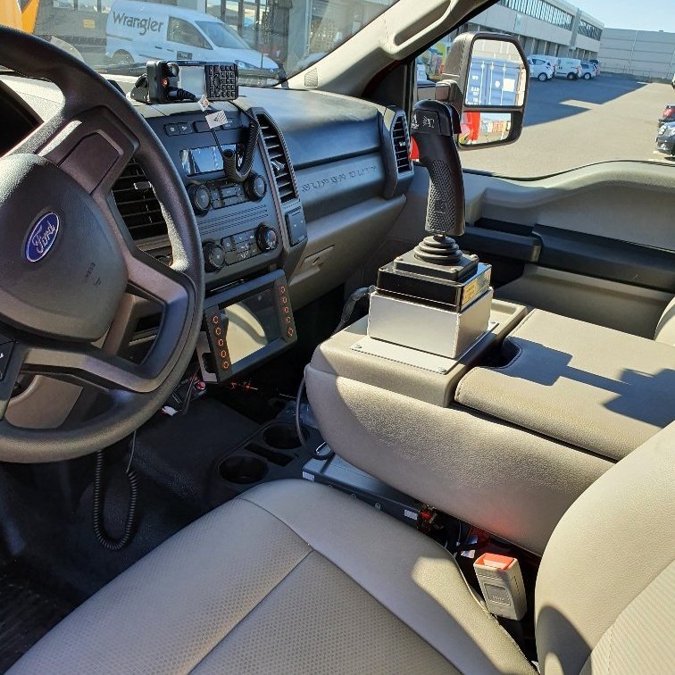 Séð inn í ökumannshús, stýripinni fyrir úðabyssu, skjár fyrir bakkmyndavél og hitamyndavél. Stjórnskjár fyrir dælu og One seven.